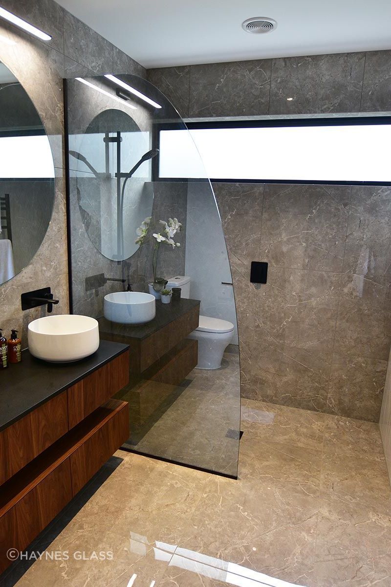 Tinted and curved, this glass shower screen adds a touch of personality to the bathroom.
