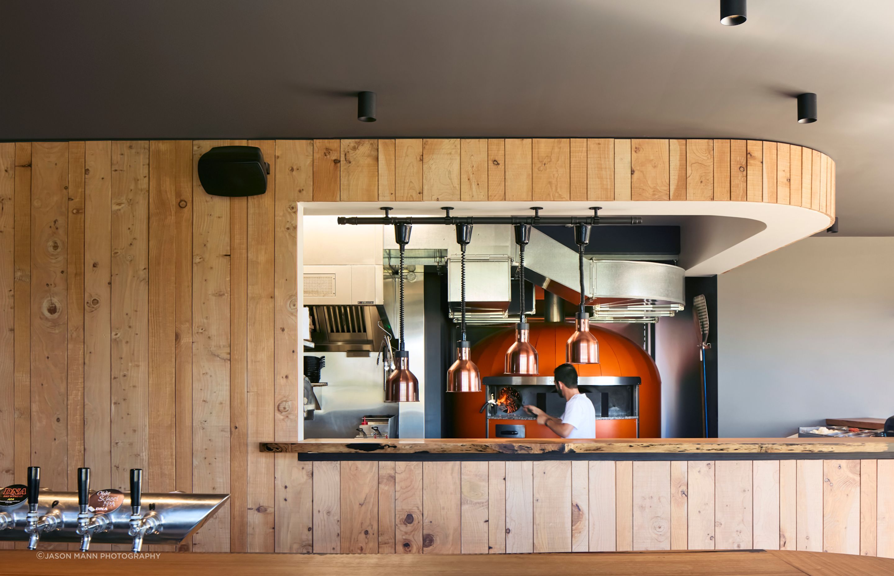 The commercial kitchen is on display, framed by Himalayan cedar panelling felled on the client's farm.