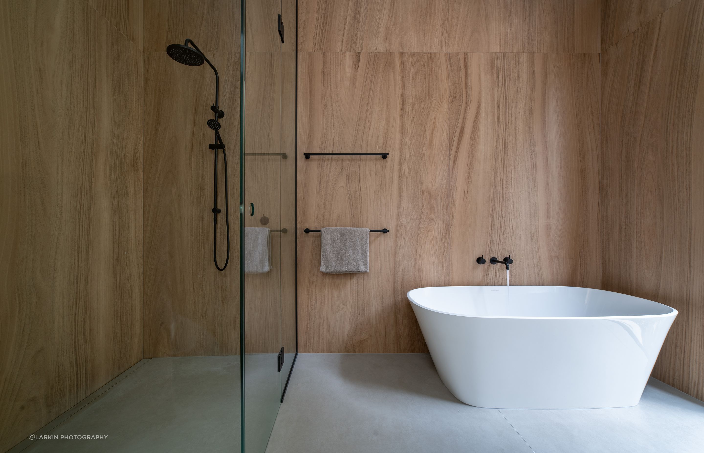 The bathroom continues the minimal approach to interior design with large format timber-look tiles and glass.