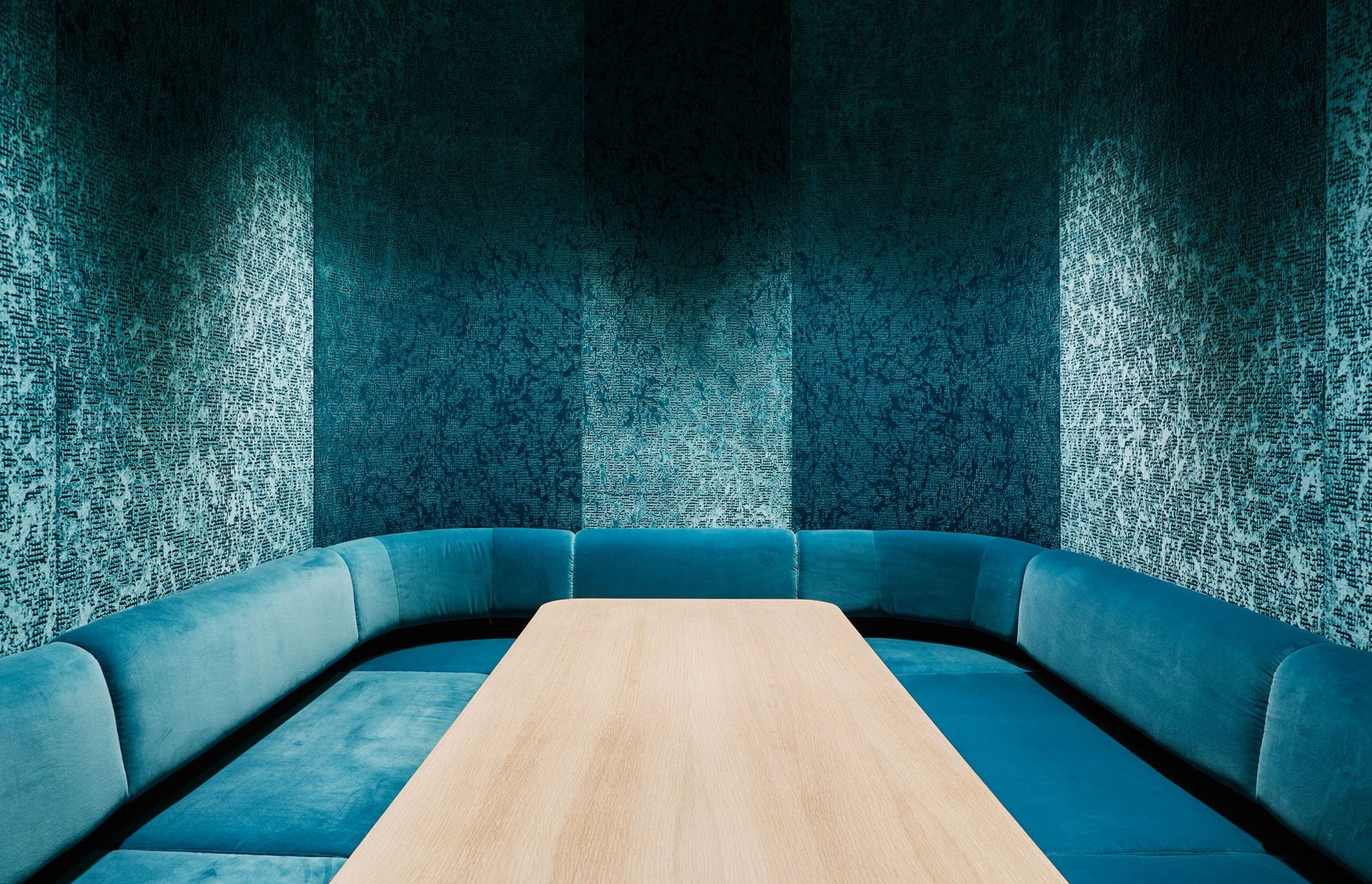 Inside the internal pod is an informal meeting booth lined with plush teal-blue seating.