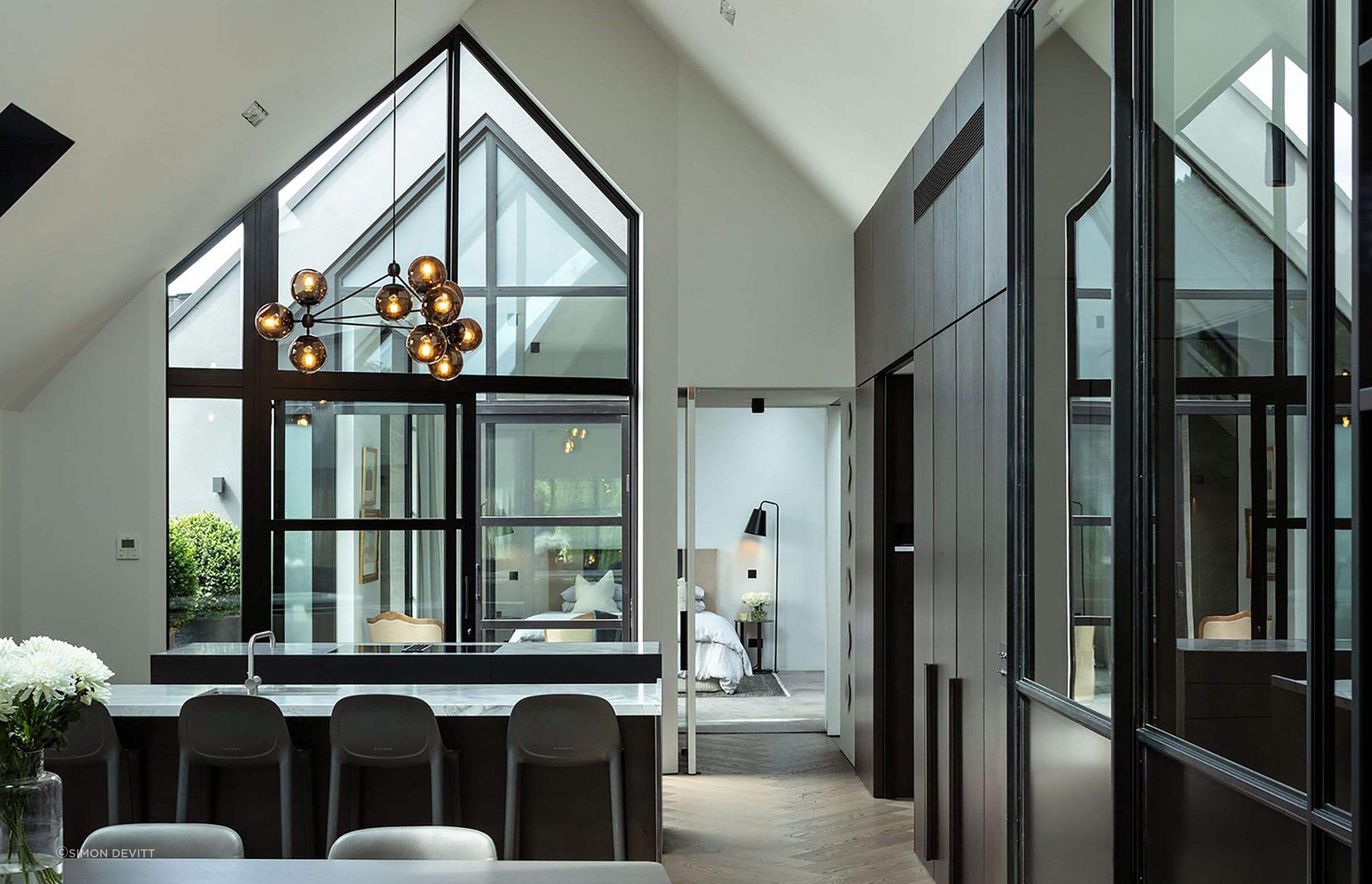 The  minimalist kitchen is a celebration of smooth and textural surfaces that play with the light drawn in from two sides and above.the double-height gabled window.
