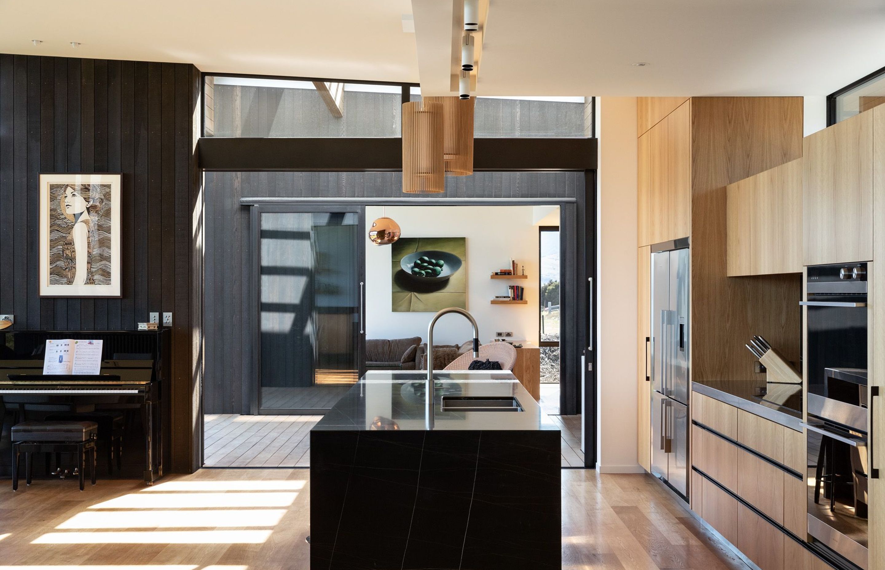 The kitchen gets east-facing morning sun through high windows over the cabinetry, and north-facing sun through high windows above the doors to the outdoor entertaining area. 