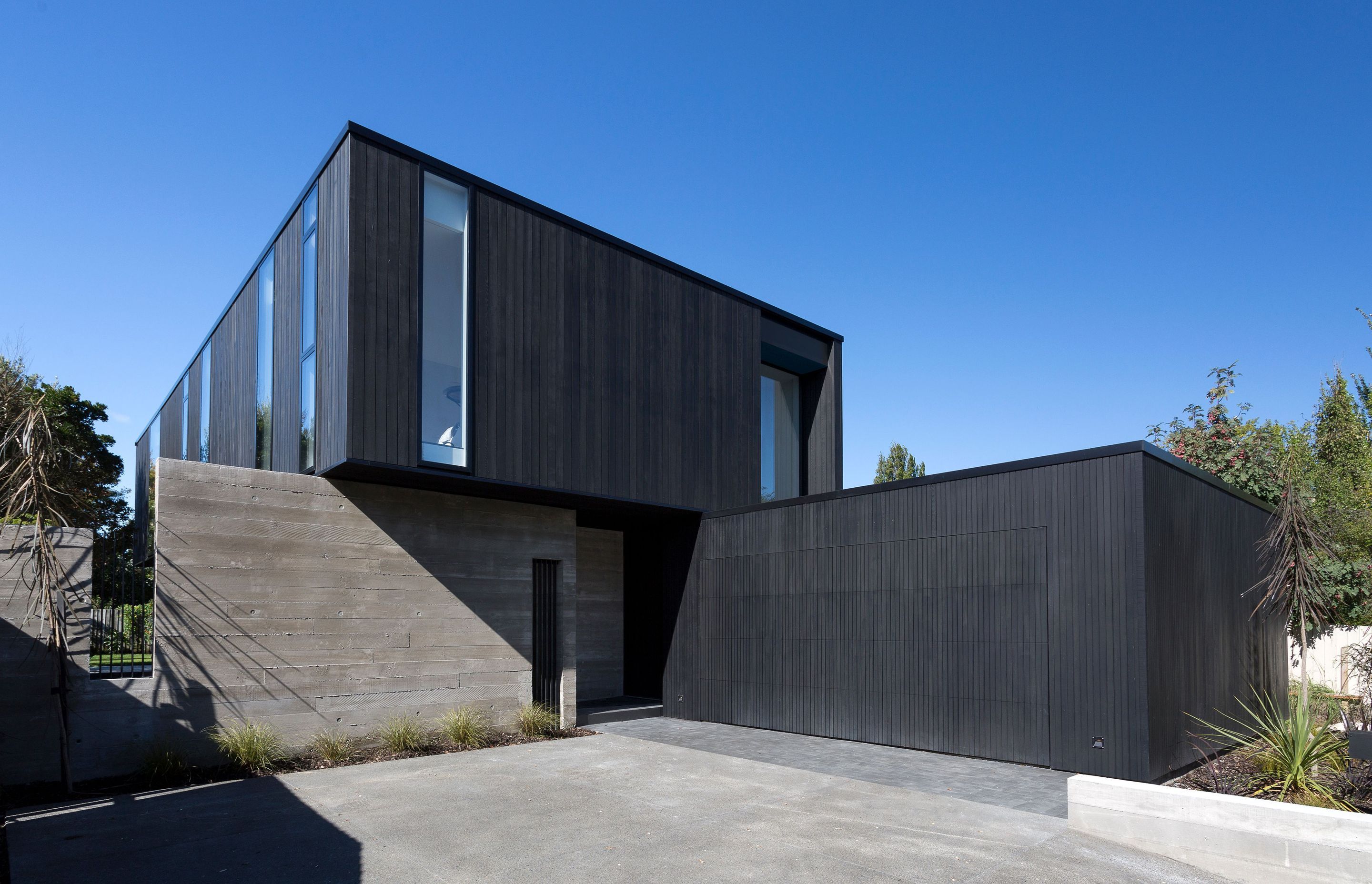 The verticality of the cedar and glass is contrasted by the horizontality of the concrete walls. A discreet garage door becomes a flat black cedar wall when closed.