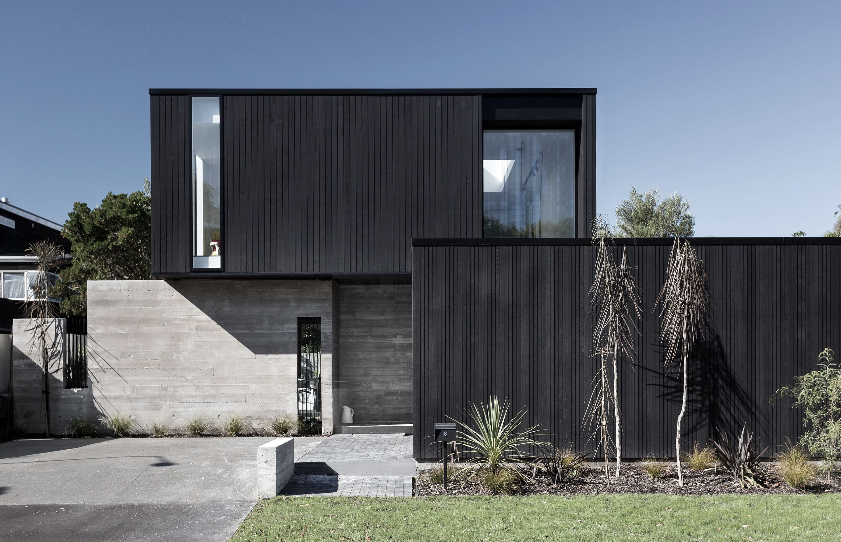 Churchill is comprised of a black cedar-clad box lightly resting over two in-situ concrete walls, with another black box out front forming the garage and boundary fence.