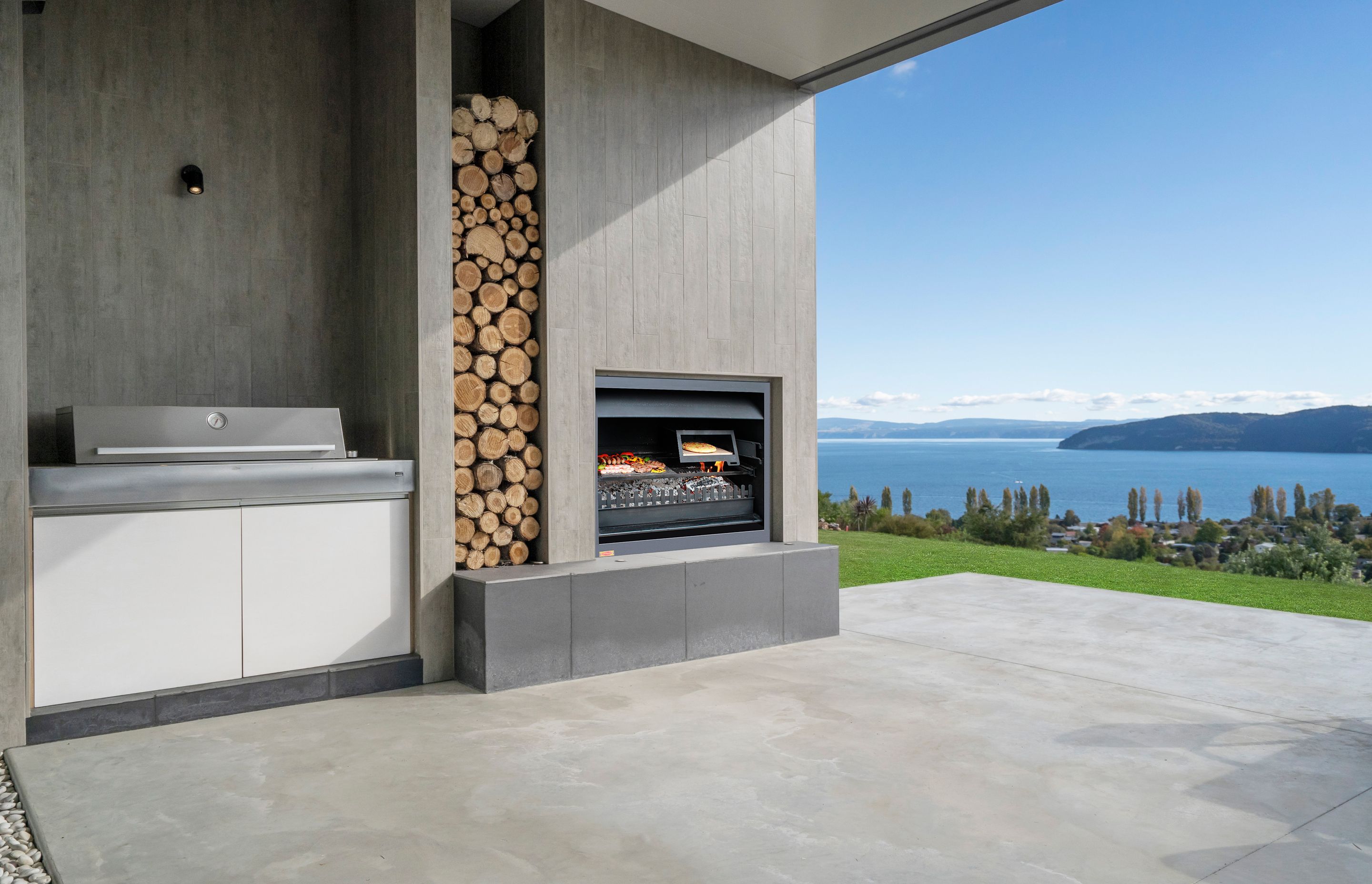 The outside kitchen, BBQ and dining area expands into lawn and overlooks Lake Taupo. Photograph: ArchiPro