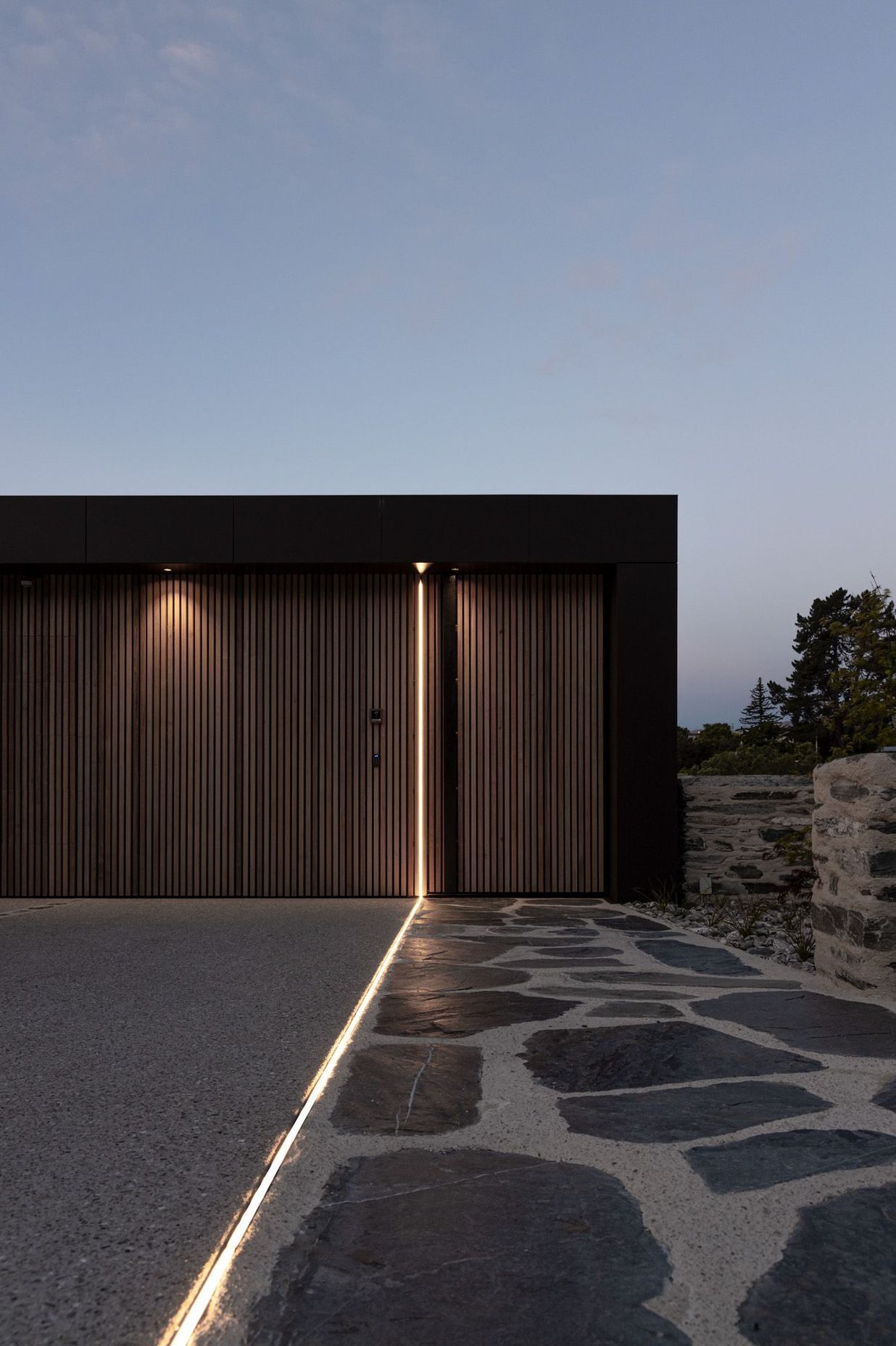 At night, a saber of light travels down the discreet garage doors and along the entry pathway.