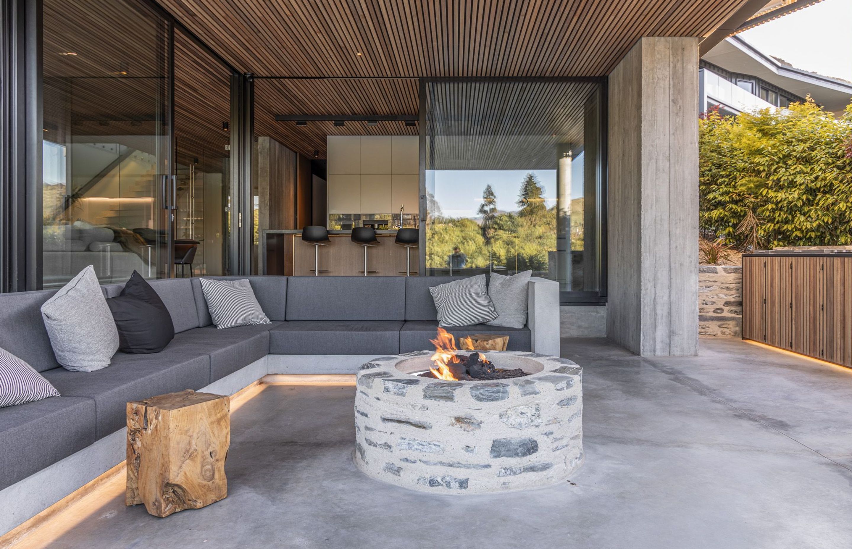 Underneath the cantilevered roof, the sheltered outdoor room features built-in furniture and a schist fire pit.