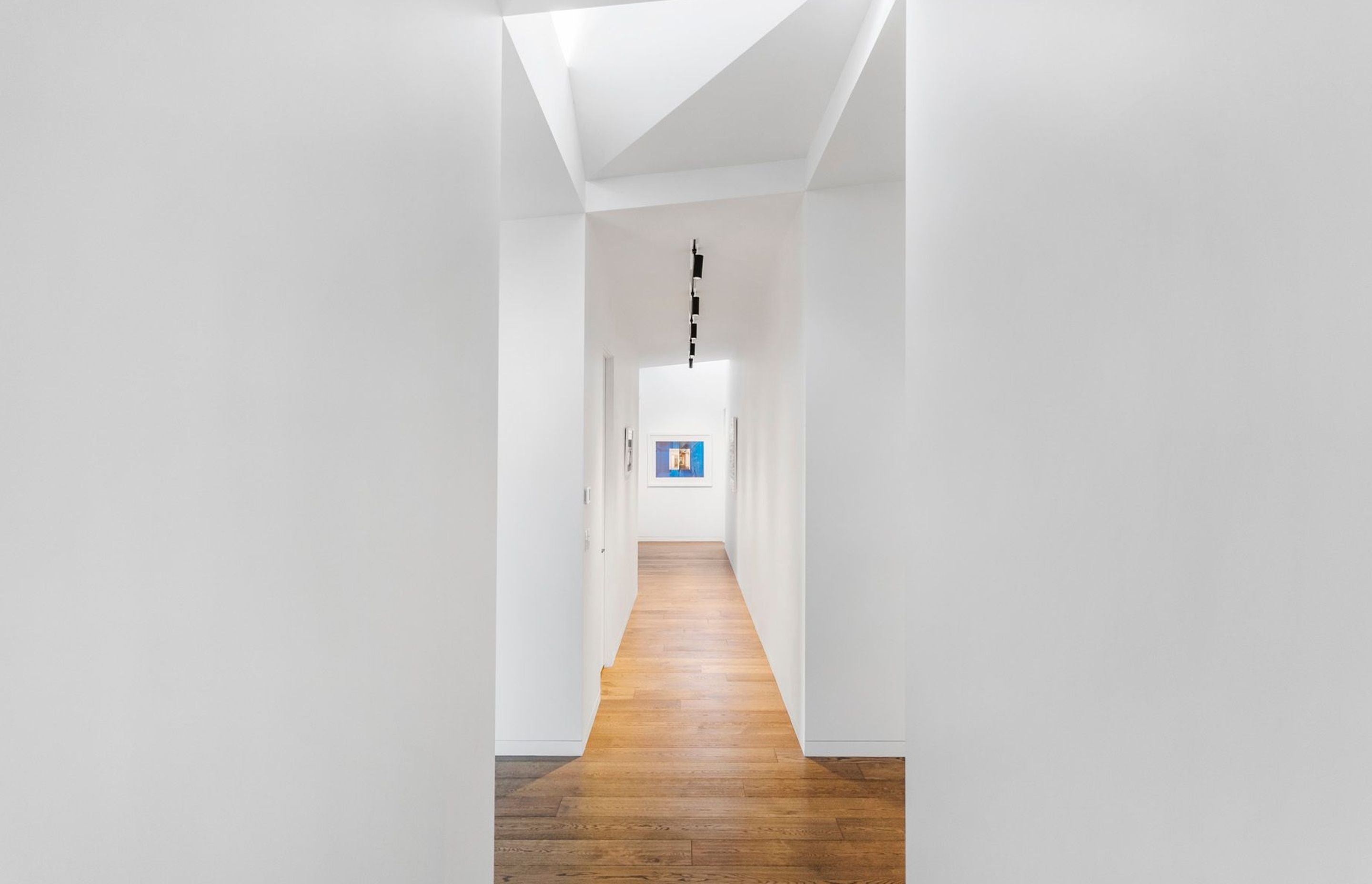 Two triangular skylights, one in the entranceway and the other at the end of the hallways, create a light-filled gallery space, perfect for showing the owner's art collection.