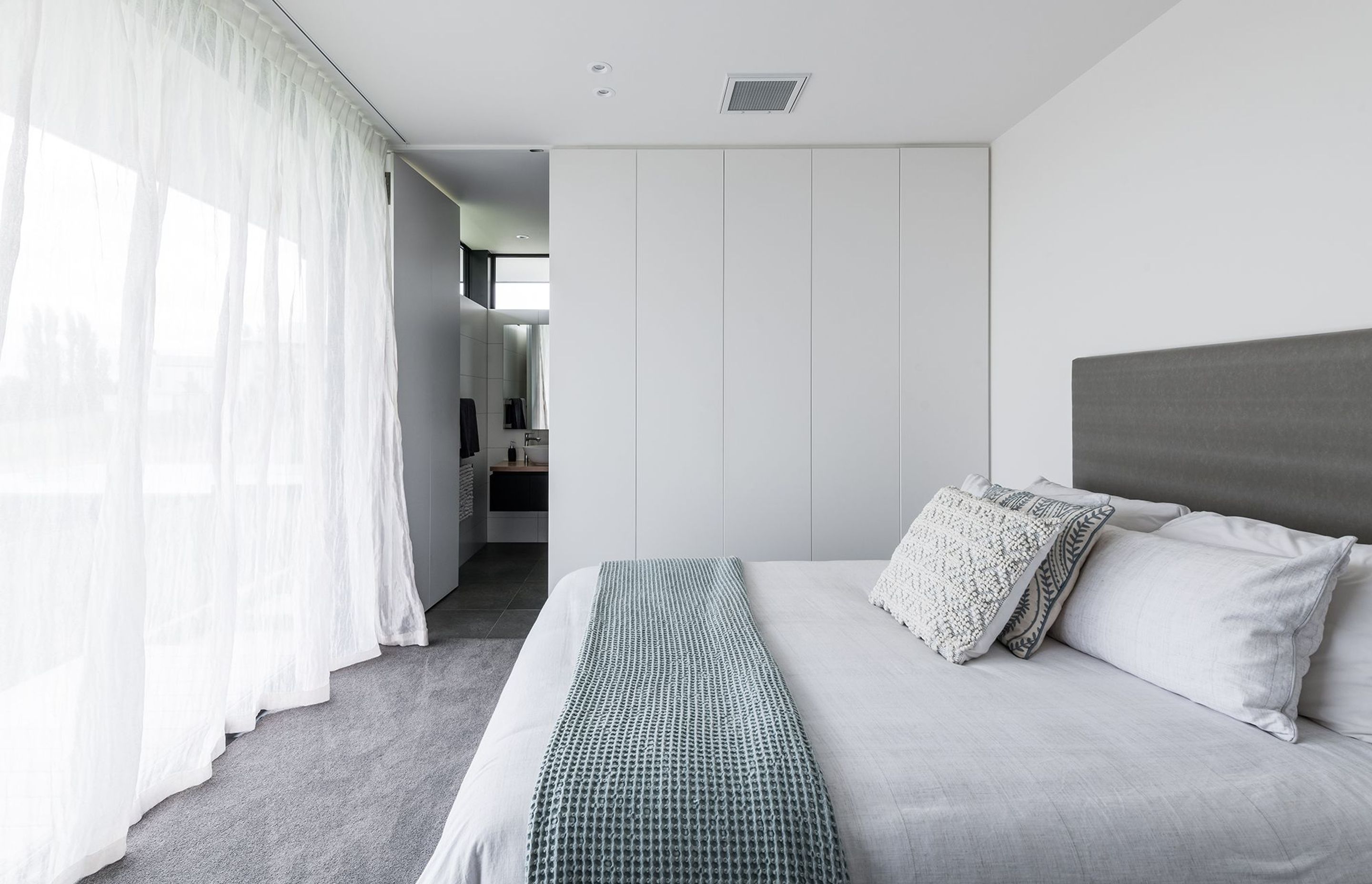 The bedroom is crisp and ethereal in white with soft tones of green and grey.