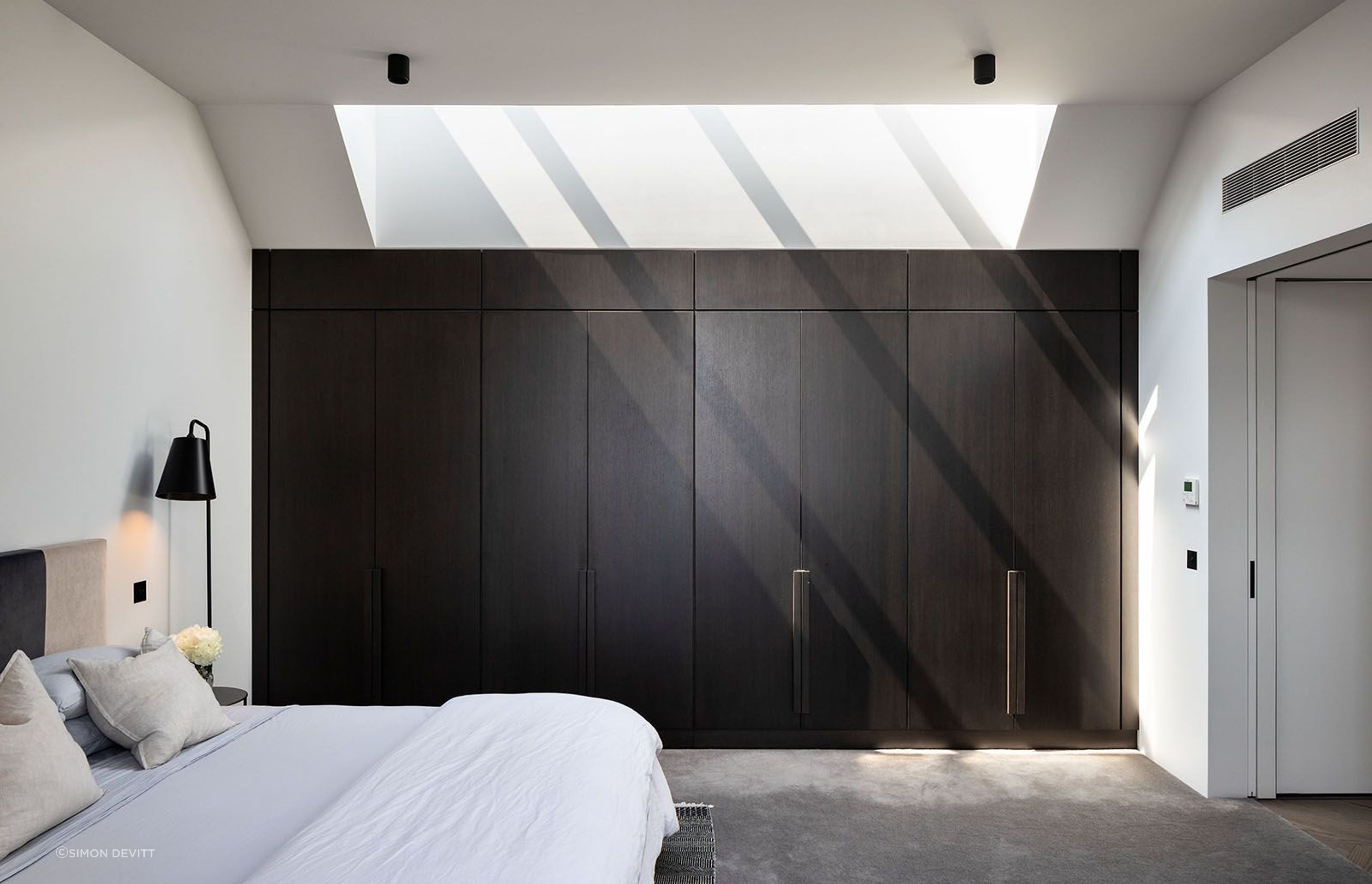 The master bedroom offers a continuation of the dark palette but creates a softness of light and texture.