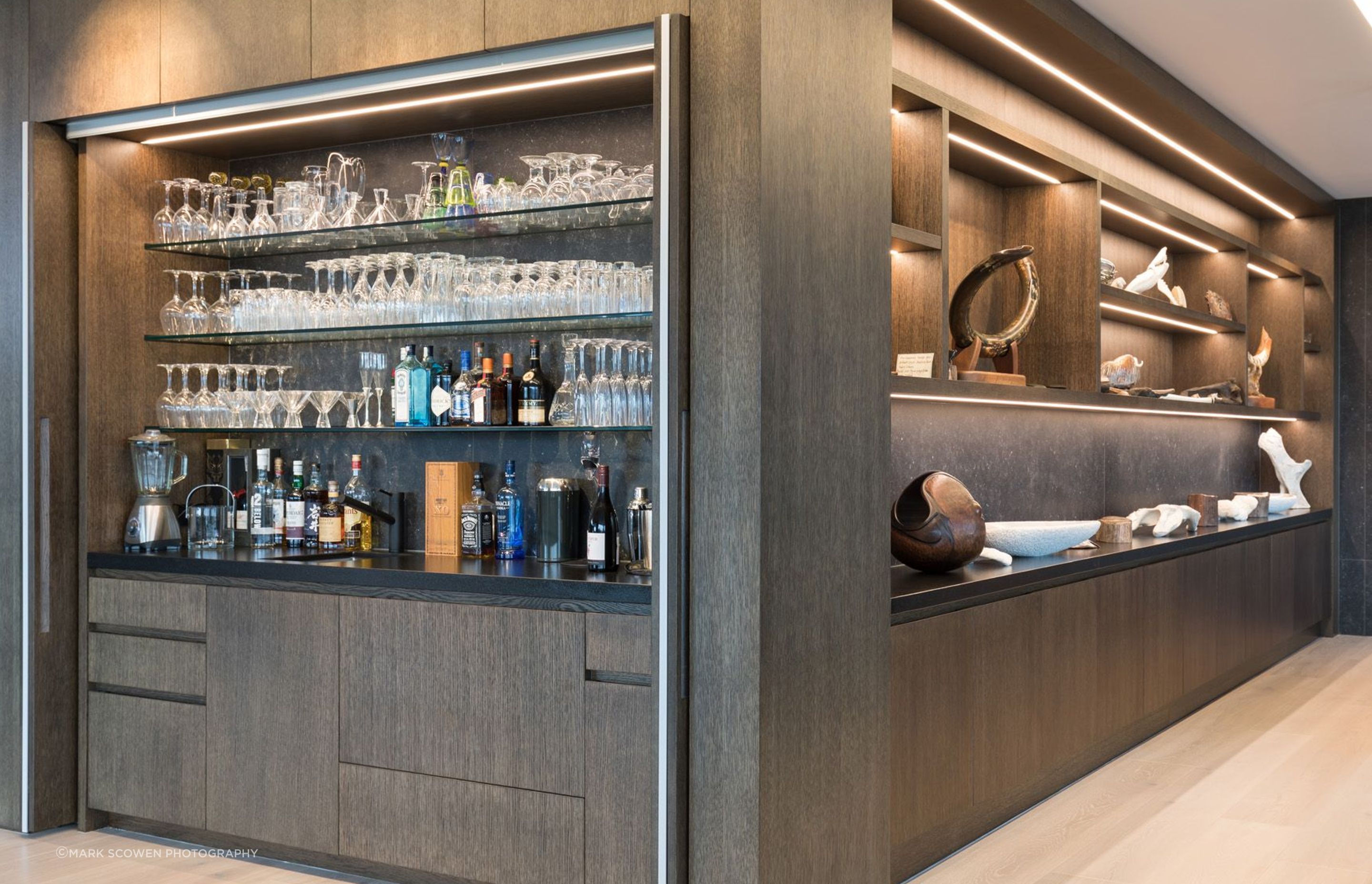 The bar next to the coffee station features doors that slide back into the walls. To the right, the owner's collection of artworks have a special display cabinet in the lounge.