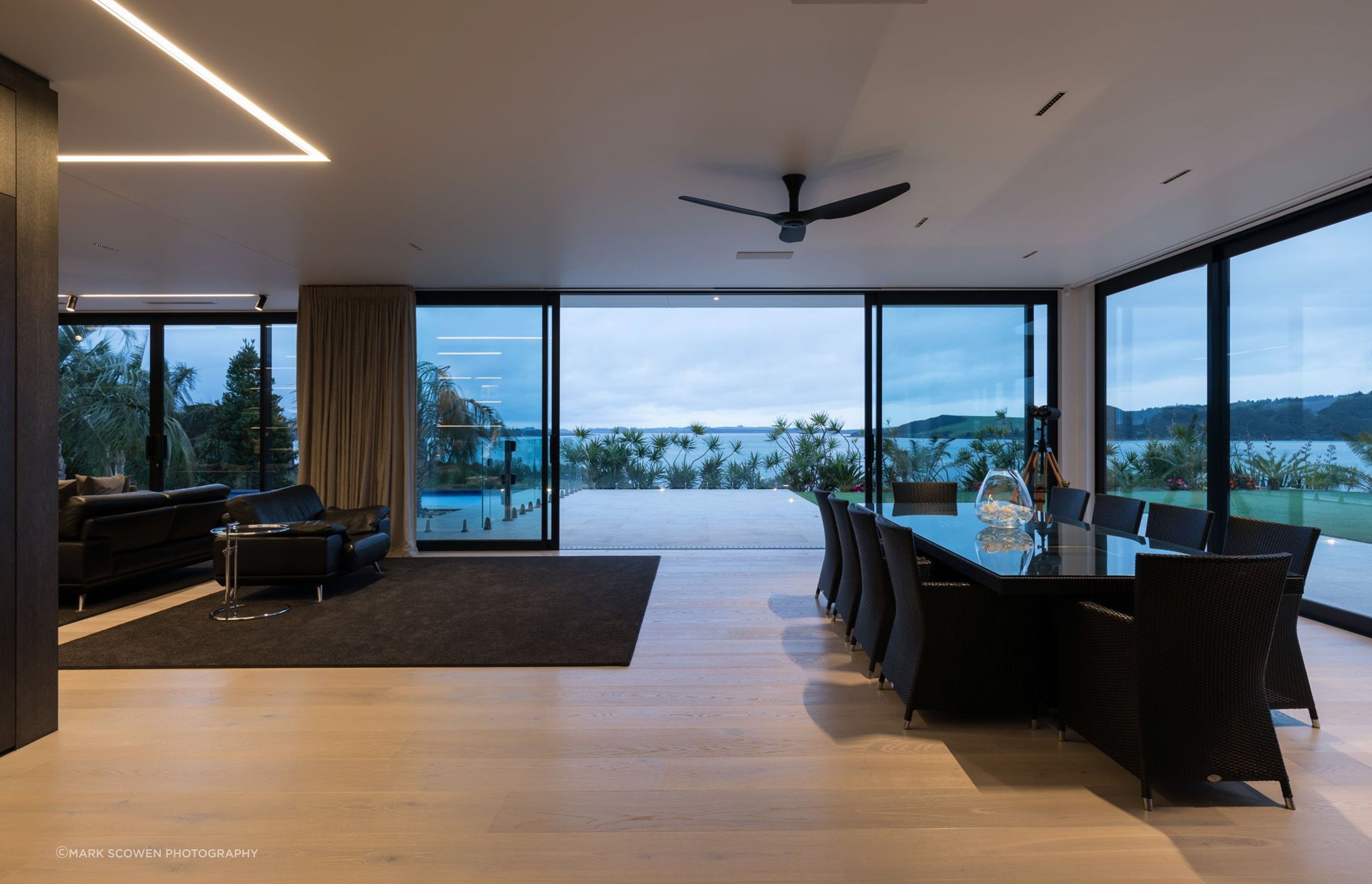 The entire open-plan dining and lounge area opens up with floor-to-ceiling doors to the harbour, the swimming pool area and a large lawn.