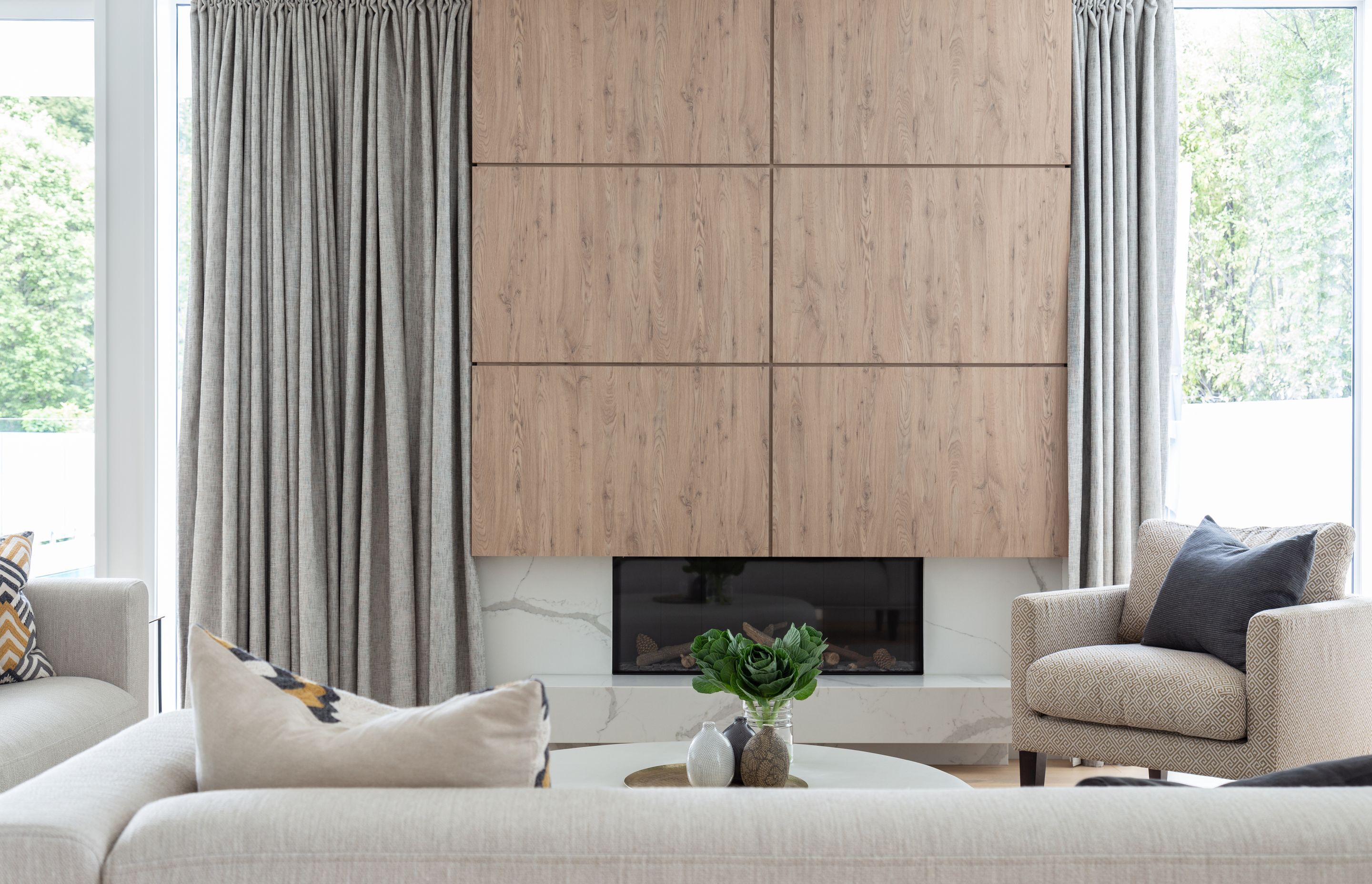The warm timber paneling of the fireplace juxtaposes against the elegant marble hearth.