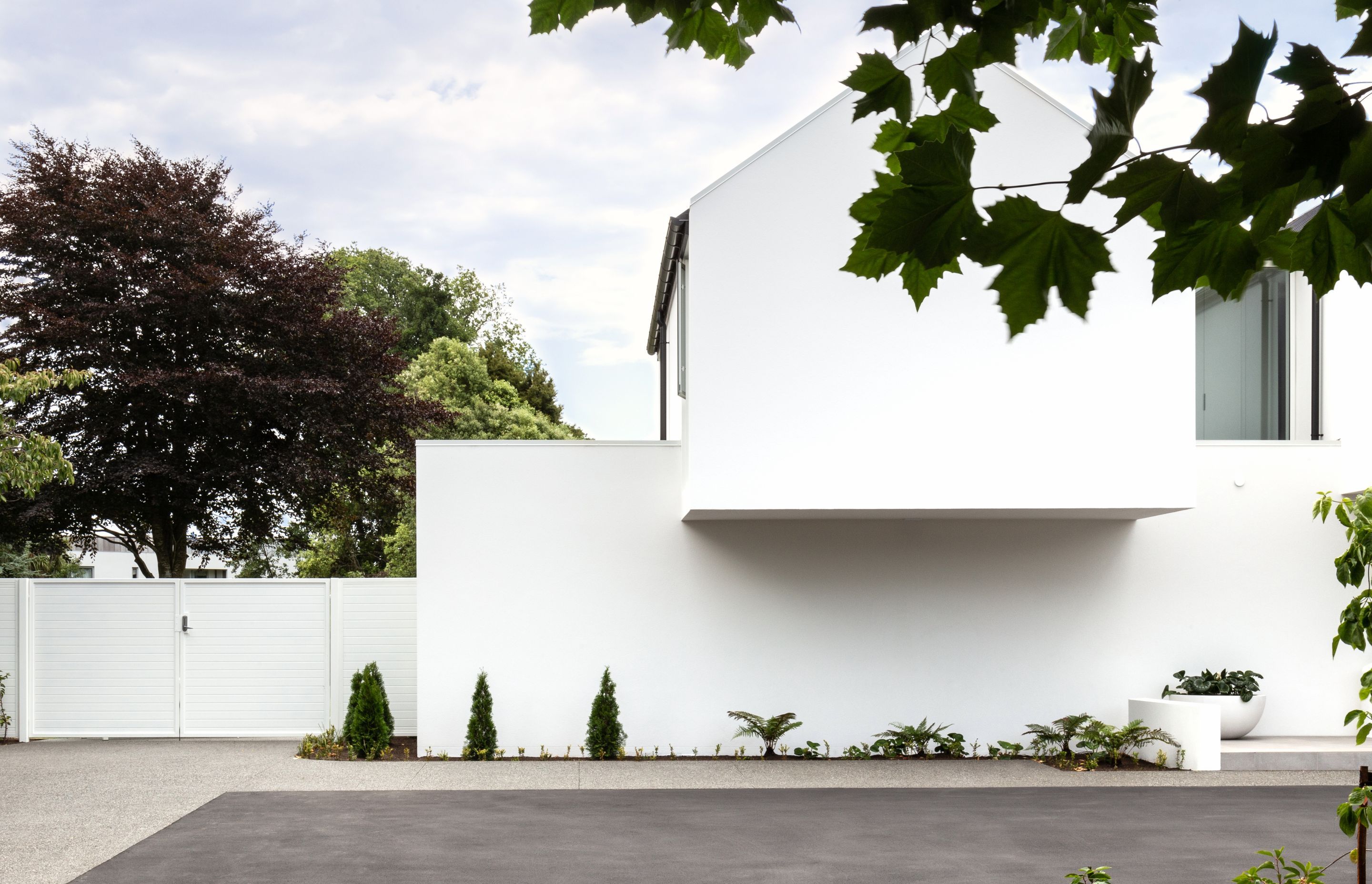 The single tone white plaster finish creates a cohesiveness to the different shapes of the home's form.