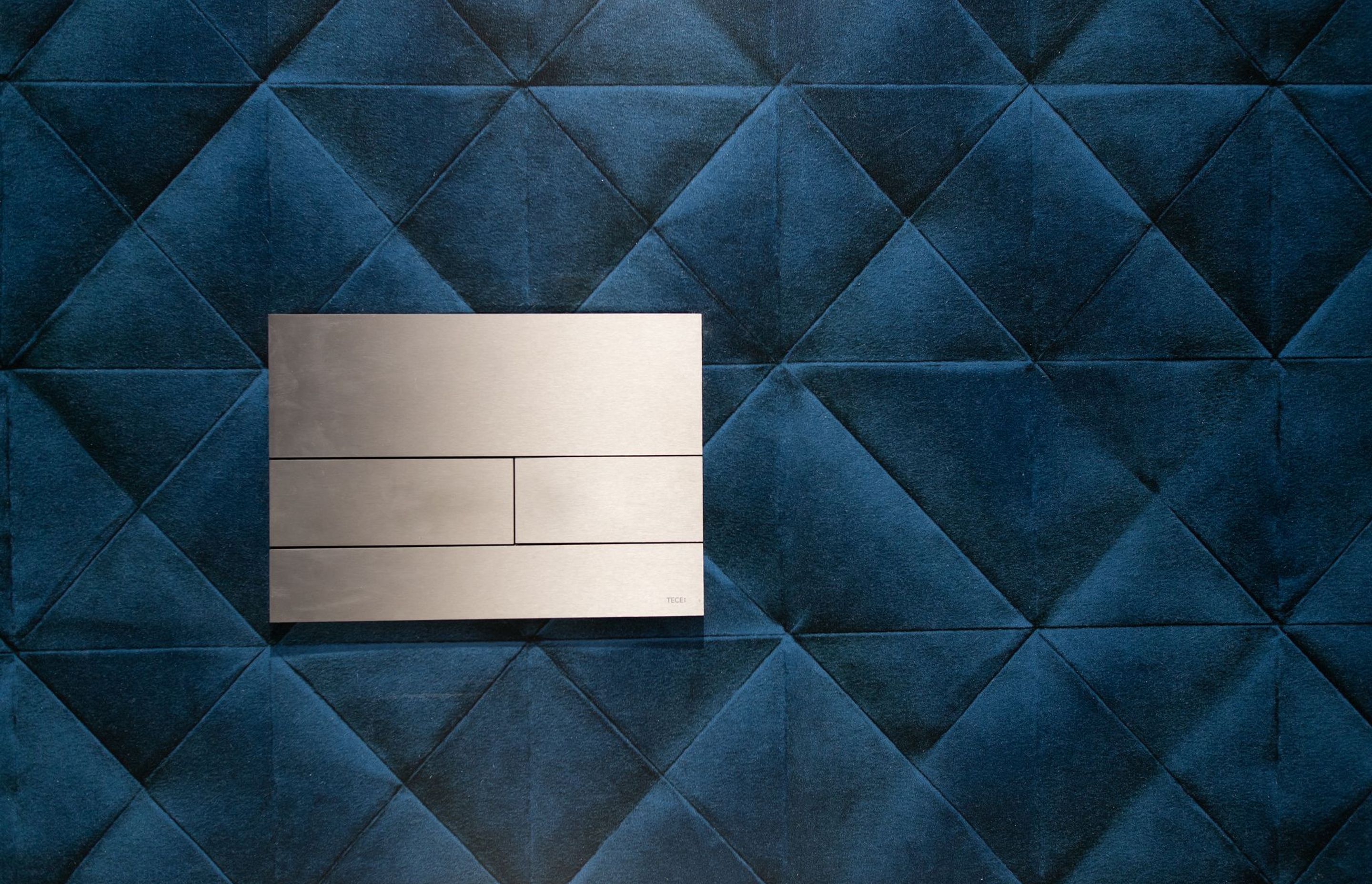 The statement wallpaper adds a further layer of plush elegance with its quilted velvet appearance.