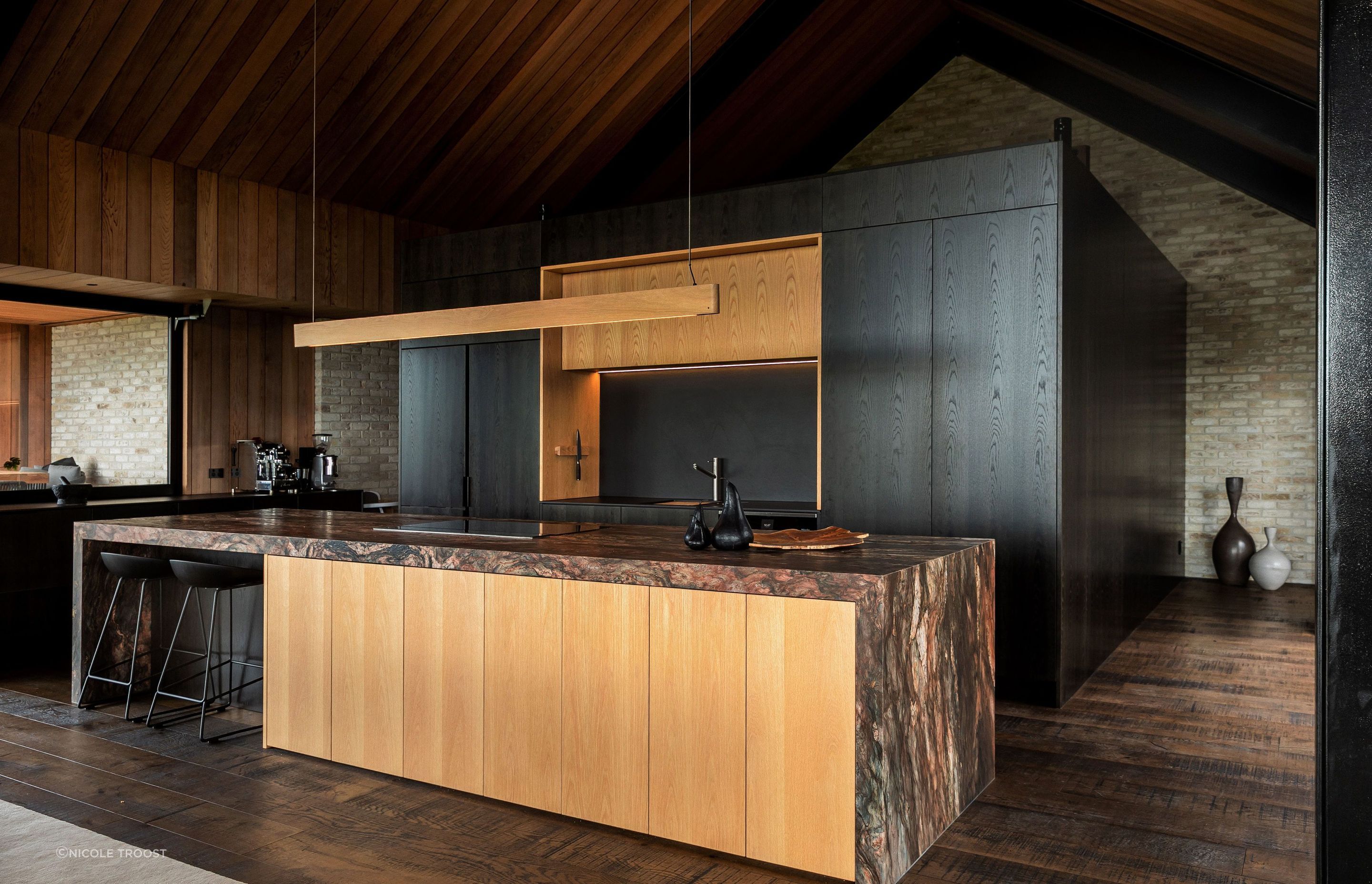 The kitchen features a stunning stone kitchen island juxtaposed against light and dark timber veneer cabinetry.