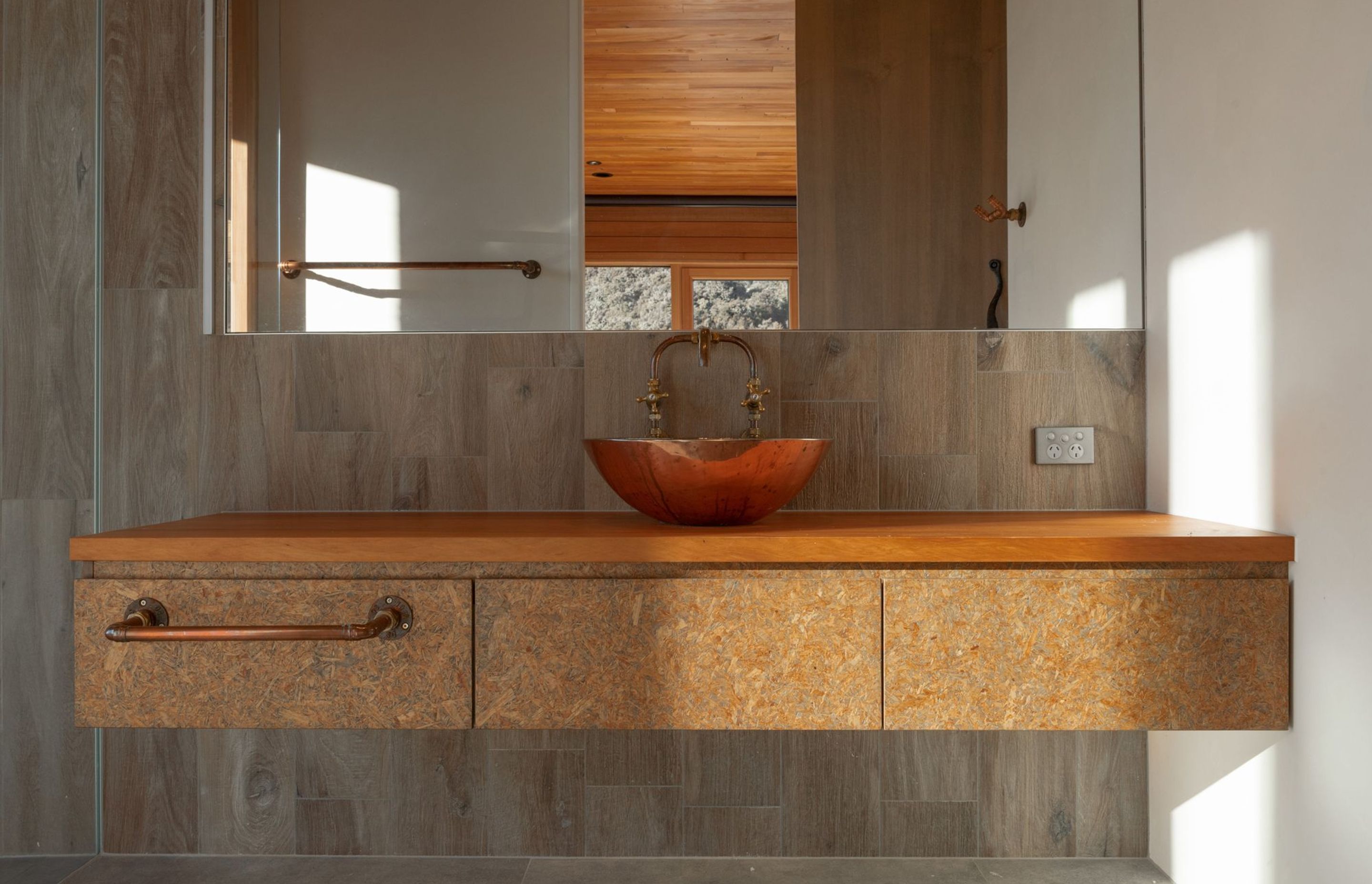 The ensuite features a custom strand board vanity and a handmade copper vessel basin.