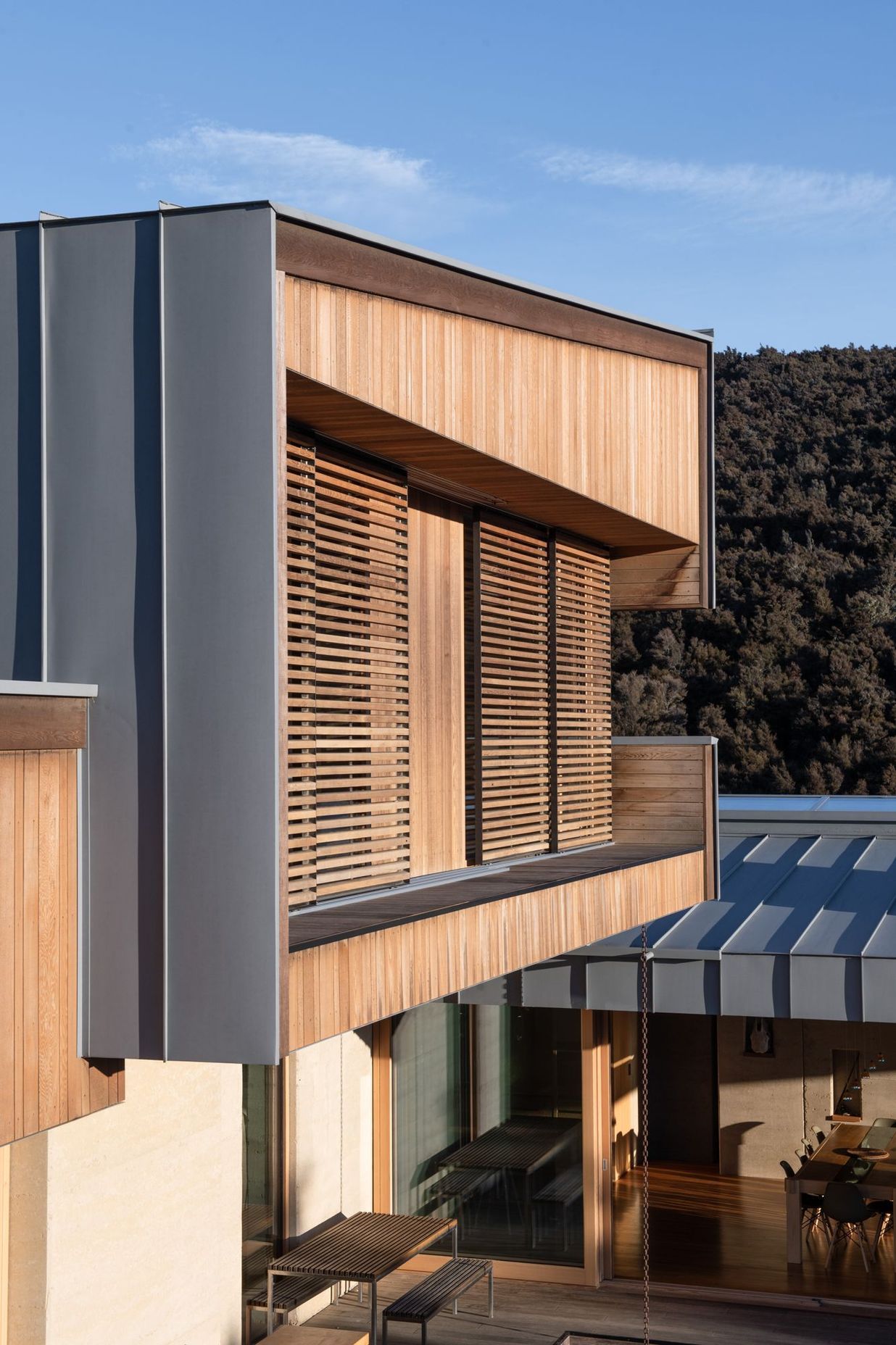 The exterior material palette comprises rammed earth, timber and zinc-coated aluminium.