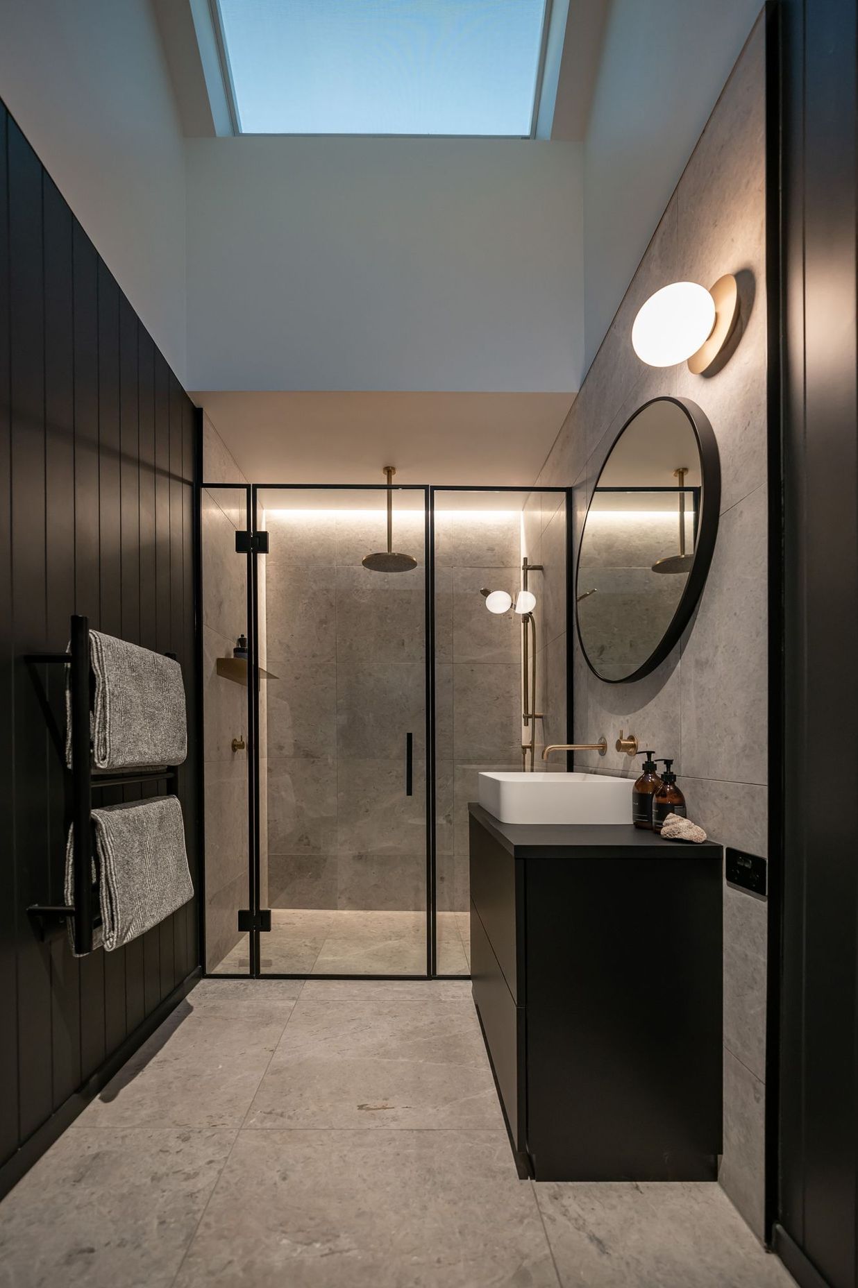 The master bathroom creates a mood through dark colours and luxury tiling.