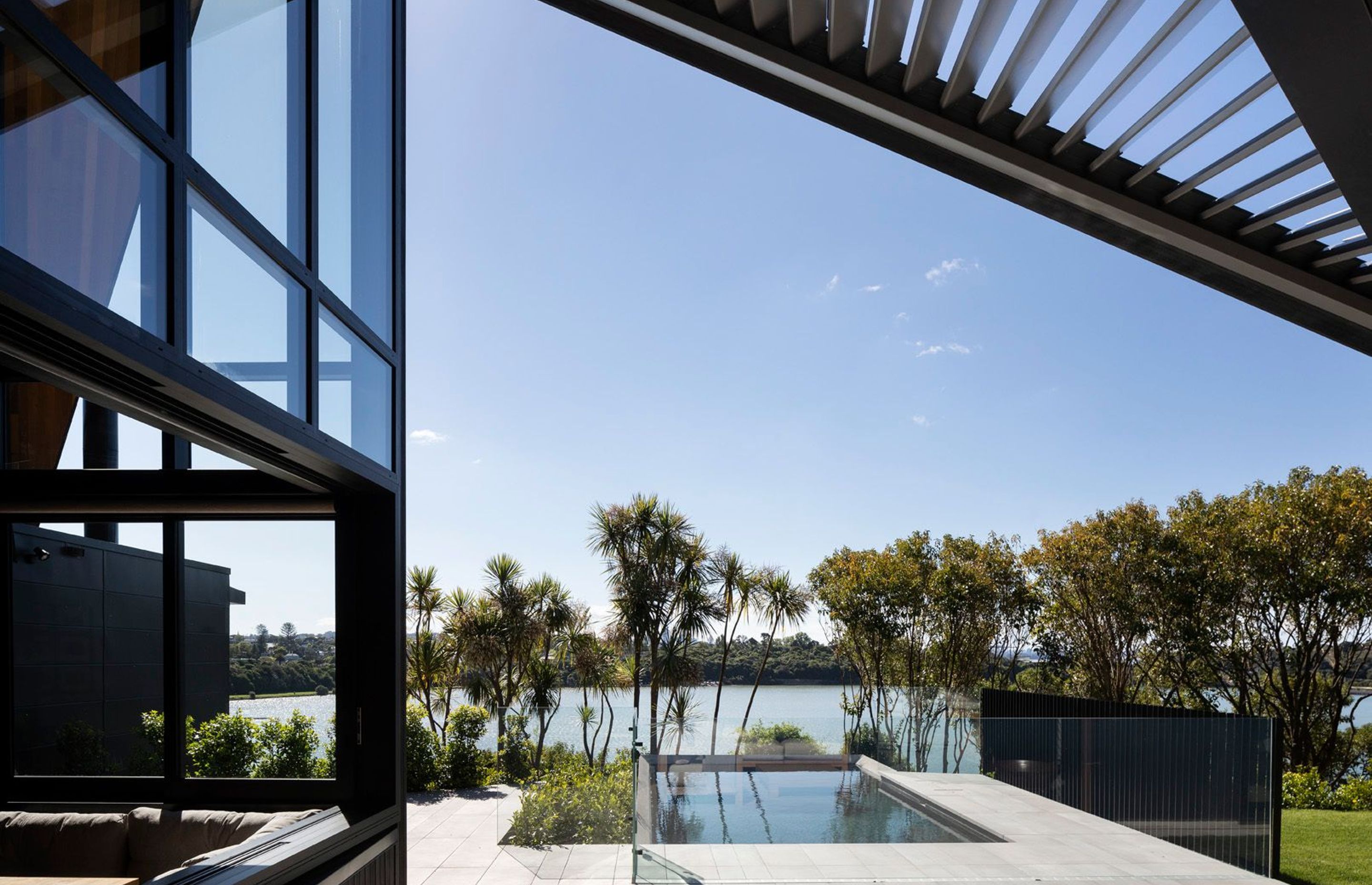 Operable louvres above the outdoor room allows morning sun to penetrate into the dining room while the view beyond the pool takes in the Orakei Basin.